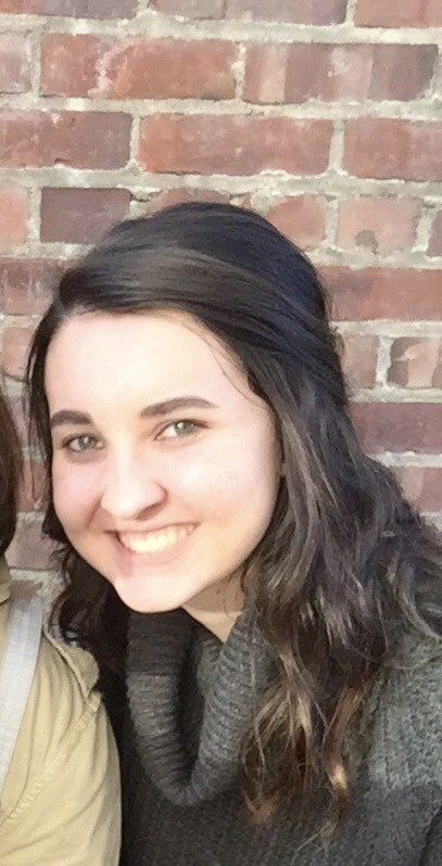 girl smiling in front of brick wall