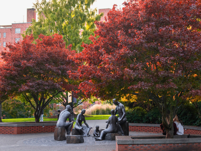 A bronze sculptural group under trees with fall leaves