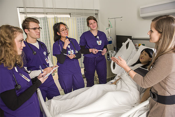 Nursing student working with a faculty member in with pediatric manikin